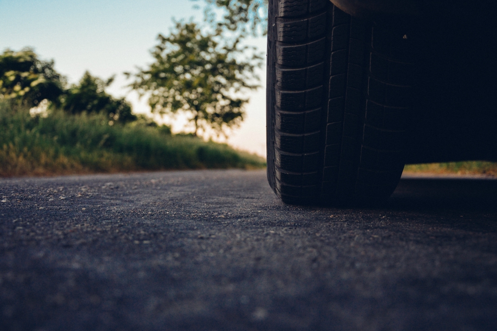 closeup of car tire atop black asphalt