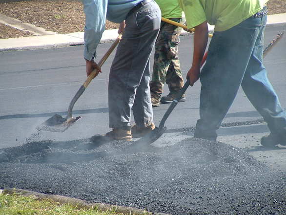 multiple people shoveling asphalt